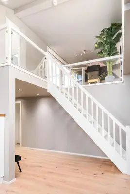 a white staircase in a living room with a potted plant at Two bedroom penthouse with large living room and rooftop in the city centre of Trondheim in Trondheim
