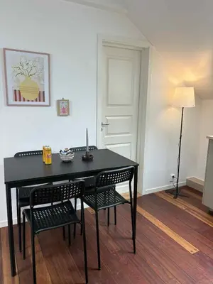 a black dining room table with two chairs and a lamp at In the middle of Bergen City in a real Bergenshus from the 18th Century in Bergen