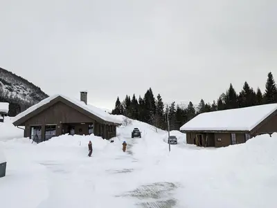 a group of people standing in the snow in front of buildings at 2 Cabins surrounded by beautiful nature in Stryn