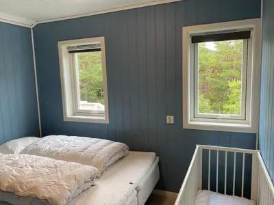 a bedroom with two beds and two windows at Bjørnafjorden