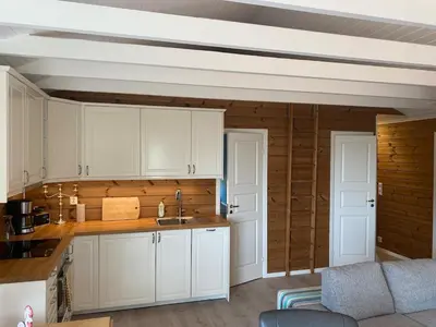 a kitchen with white cabinets and wooden walls at Bjørnafjorden