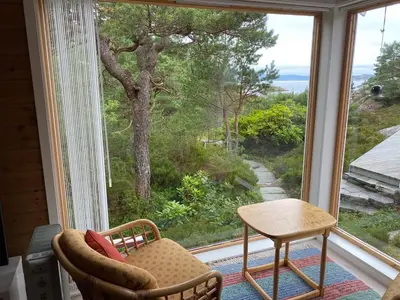 a room with a window with a chair and a table at Bjørnafjorden