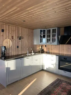 a kitchen with white cabinets and a wooden ceiling at Stylish Cabin With Lovely View At Stavadalen in Reinli