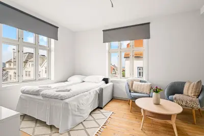 a white bedroom with a bed and two chairs and a table at Authentic Bergen Charm in Famous Neighborhood in Bergen