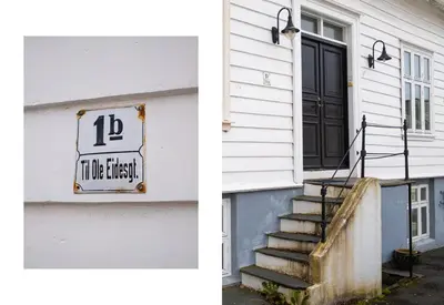 a white house with a black door and a sign on it at Authentic Bergen Charm in Famous Neighborhood in Bergen