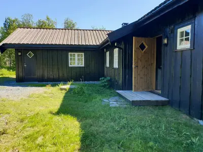 a black house with a wooden door and a yard at Mountain Cabin With Views Over Storevann in Hemsedal