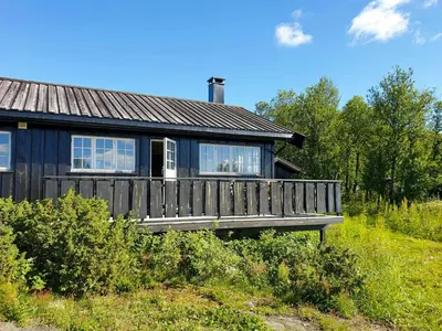 a small house with a wooden deck in a field at Mountain Cabin With Views Over Storevann in Hemsedal