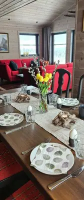 a wooden table with plates of food and flowers on it at New Cabin With Panoramic Views Of Lake Osen