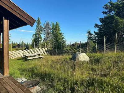 a picnic table and a bench in a field with a fence at Family Cabin With Charm in Mesnali