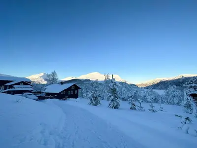 a cabin in the snow with mountains in the background at Relaxing Mountain Cabin In Scenic Surroundings in Stranda