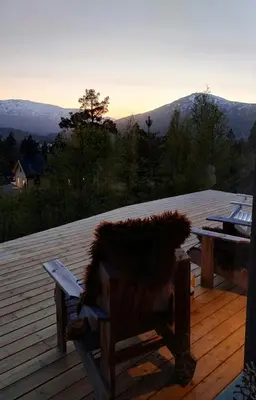 a wooden bench sitting on a deck with a table at Mountain Cabin With View At Bjorli in Bjorli