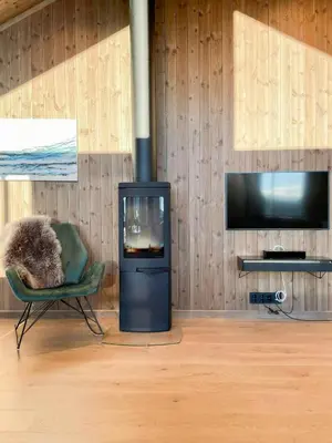 a room with a chair and a fireplace and a television at Cabin With Views Over Hafjell And Gausdal in Svingvoll