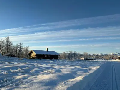 a snow covered field with a barn in the background at Traditional Log Cabin At Reineskarvet in Ål