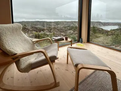 a living room with a chair and a large window at Architect-Designed Cabin Panoramic View in Ervik