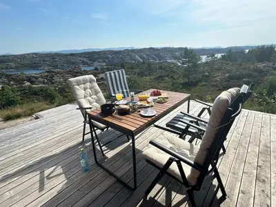 a wooden table and two chairs on a wooden deck at Architect-Designed Cabin Panoramic View in Ervik