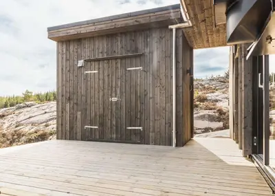 a wooden building with a door on a deck at Architect-Designed Cabin Panoramic View in Ervik