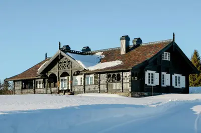 a large house with snow on the ground in front at Historic Hunting Lodge By Lake Øyangen in Gålå