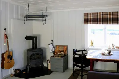 a living room with a wood stove and a desk at Historic Hunting Lodge By Lake Øyangen in Gålå