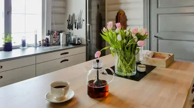 a table with a vase of flowers and a cup of coffee at Historic Hunting Lodge By Lake Øyangen in Gålå