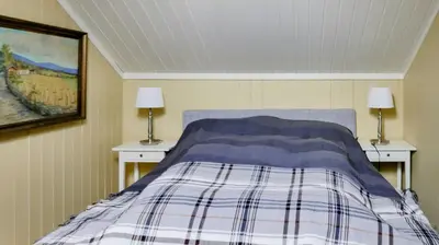 a bedroom with a bed with two nightstands and two lamps at Historic Hunting Lodge By Lake Øyangen in Gålå