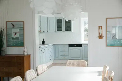 a kitchen with blue cabinets and a table and chairs at Kommahuset in Ervik