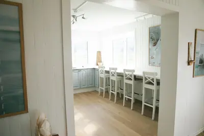 a kitchen with white cabinets and a table and chairs at Kommahuset in Ervik