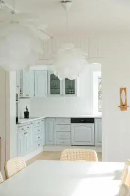 a kitchen with white cabinets and a table with chairs at Kommahuset in Ervik