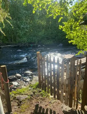 a fence in front of a river next to a river at Idyllic house in Hurdal 2 bedroom in Hurdal