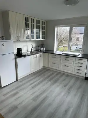 a kitchen with white cabinets and a wooden floor at Sula in Frøya
