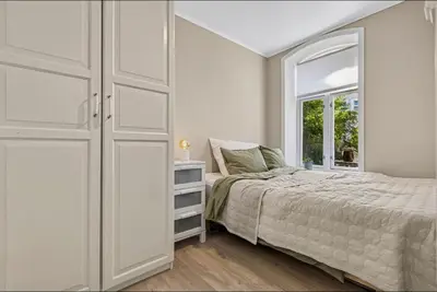 a white bedroom with a bed and a window at Eden Oasis, Bakklandet with Free parking! in Trondheim