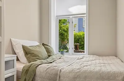 a white bedroom with a bed and a window at Eden Oasis, Bakklandet with Free parking! in Trondheim