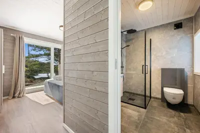 a bathroom with a toilet and a glass shower door at Ny feriehytte i skjærgården in Austevoll