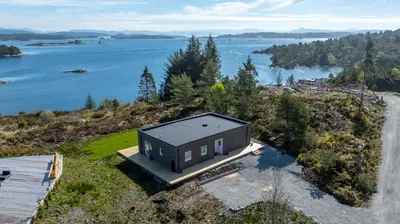 a small house on a hill next to a body of water at Ny feriehytte i skjærgården in Austevoll