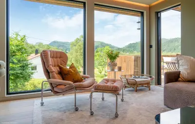 a living room with a couch and a chair and large windows at Luxurious Home In Ytre Arna With Wifi in Ytre Arna