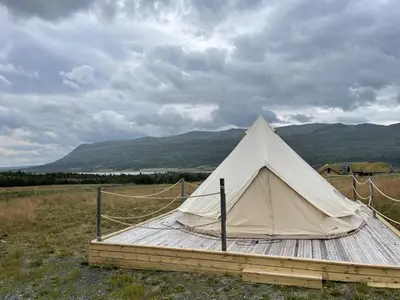 a white tent sitting on a wooden platform in a field at Syndinstøga in Ryfoss