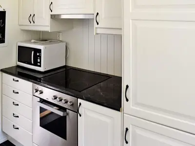 a kitchen with white cabinets and a microwave at 5 person holiday home in Oksvoll in Oksvoll