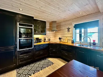 a large kitchen with wooden cabinets and a window at Indoor hot tub, views & nature, cosy family cabin at Filefjell in Tyinkrysset
