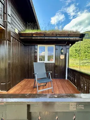 a chair sitting on a deck next to a house at Indoor hot tub, views & nature, cosy family cabin at Filefjell in Tyinkrysset