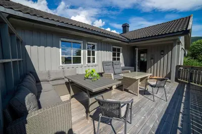 a patio with a table and chairs on a deck at Cozy house with free parking on the premises in Ringebu