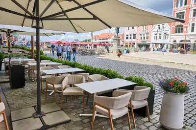 a row of tables and chairs with an umbrella at HD Central Topfloor in Bergen
