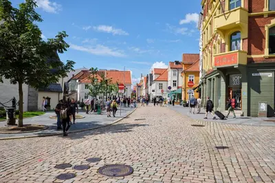 a group of people walking down a cobblestone street at HD Central Topfloor in Bergen