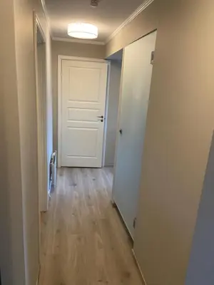 an empty hallway with a white door and wooden floors at Great and modern apartment at Grilstad Marina! in Trondheim