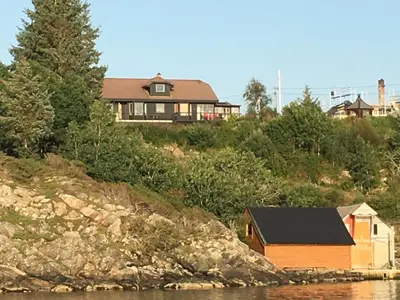 a house sitting on top of a hill next to the water at Bergtun's Corner - Sotra Vest in Sekkingstad
