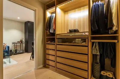 a walk in closet with wooden cabinets and a mirror at J og F in Bergen
