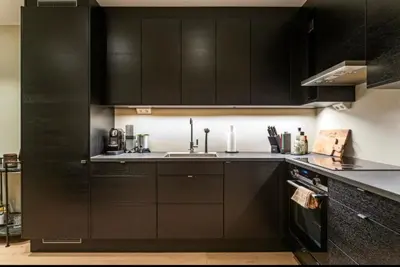 a kitchen with black cabinets and a sink at J og F in Bergen