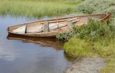 a wooden boat sitting on the side of a river at Lovely Home In Røn With House A Mountain View in Ron