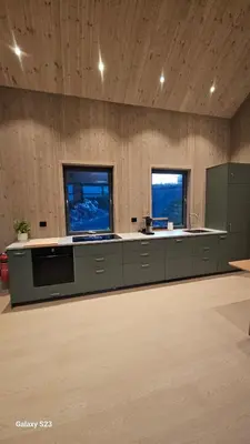 a large kitchen with a counter and two windows at Sjåen på Balsnes Gård in Hitra