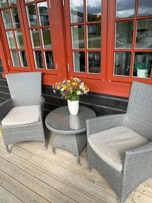 two chairs and a table with a vase of flowers on a porch at Central on Beitostølen with walking distance to everything in Beitostøl