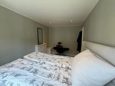 a bedroom with a bed and a desk in a room at Moderne 3-roms nær sentrum in Bergen
