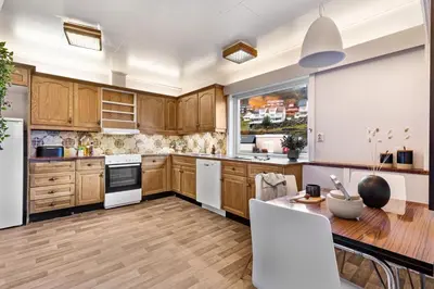 a kitchen with wooden cabinets and white appliances at Fjordside Escape - Spacious apartment with amazing views in Tysnes